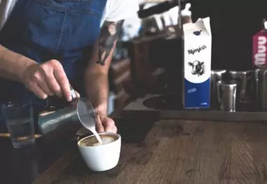 barista pours frothed milk